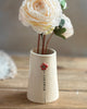 White ceramic vase with a floral design on a wooden surface