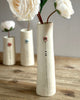 Three ceramic vases with white flowers on a wooden surface