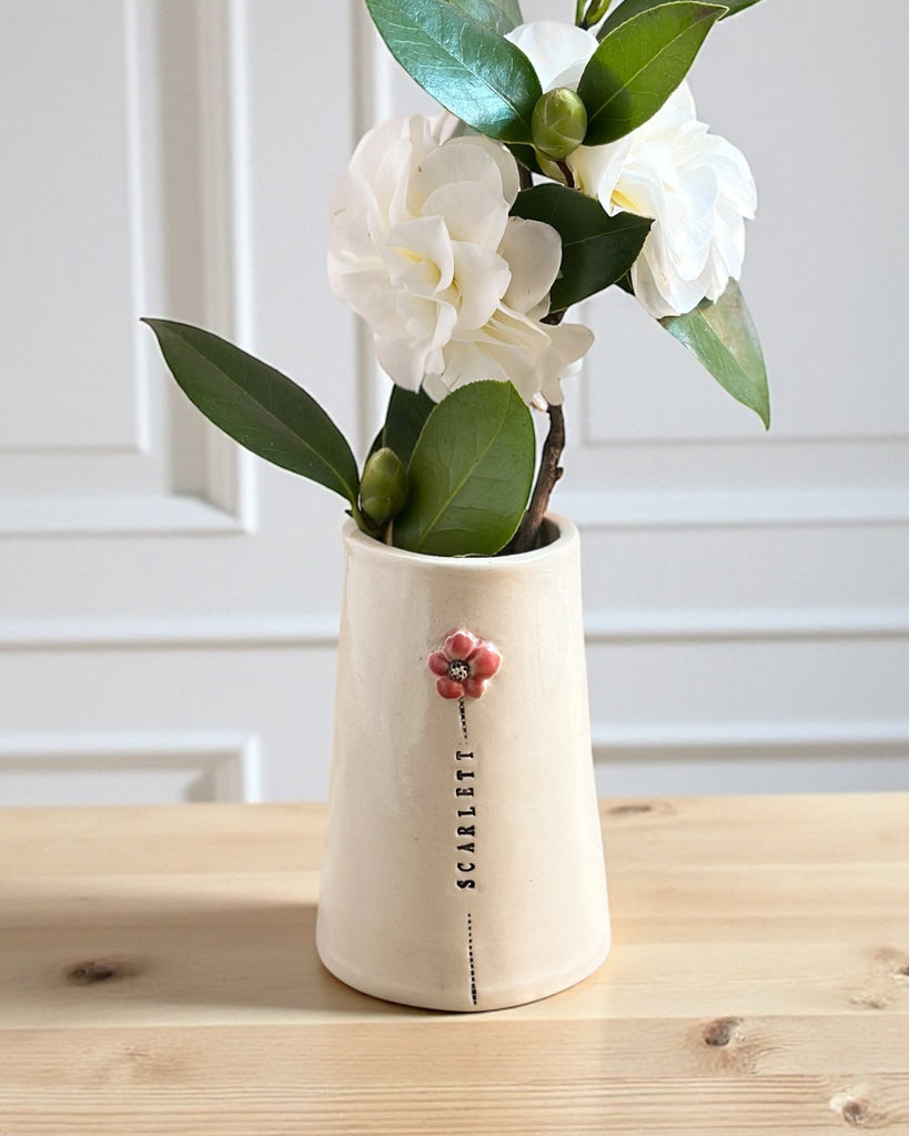 White vase with flowers on a wooden surface