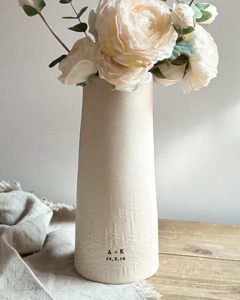 White vase with flowers on a wooden surface
