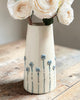 White ceramic vase with floral design on a wooden surface