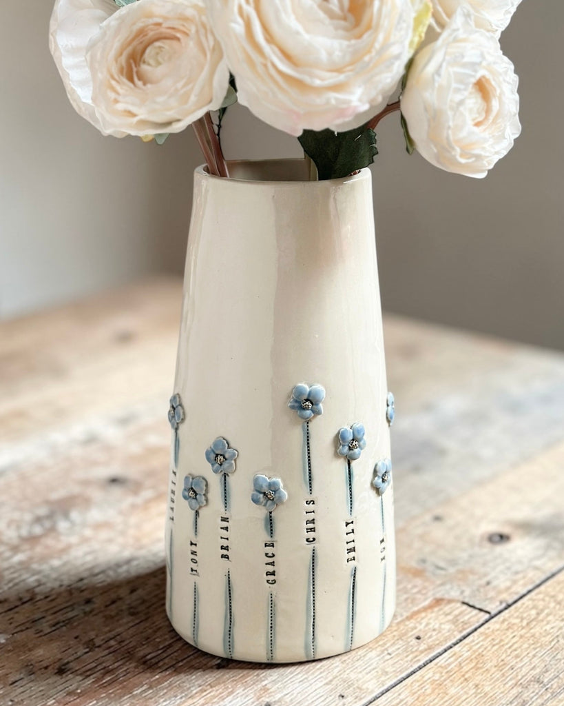 White ceramic vase with floral design on a wooden surface